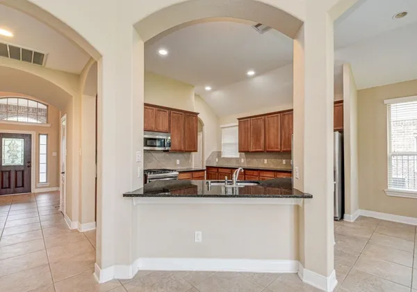 a view of a kitchen with kitchen island stainless steel appliances granite countertop a refrigerator and a sink