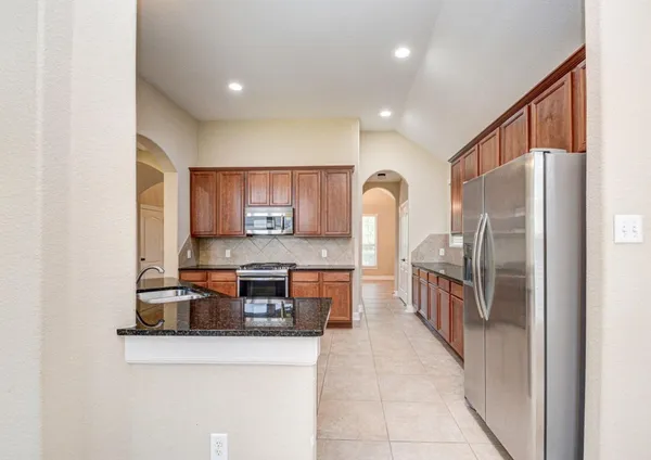 a kitchen with stainless steel appliances granite countertop a refrigerator and a stove