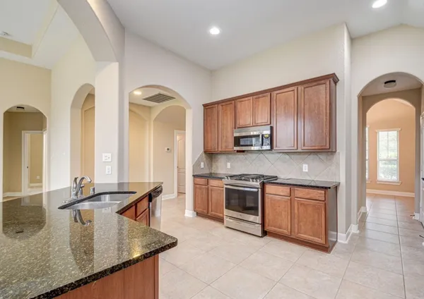 a kitchen with stainless steel appliances granite countertop a stove sink and cabinets