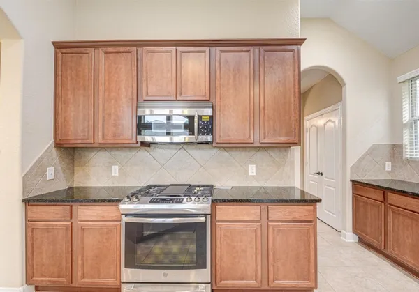 a kitchen with stainless steel appliances granite countertop a stove a sink and a microwave