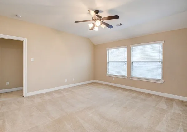 an empty room with chandelier fan and windows