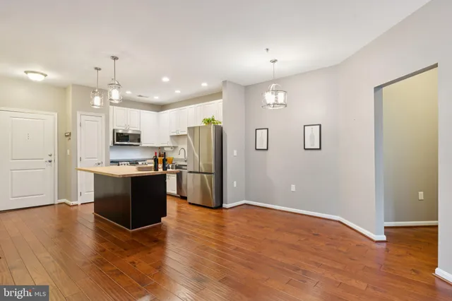 a kitchen with stainless steel appliances granite countertop a refrigerator a sink a stove and oven with wooden floor