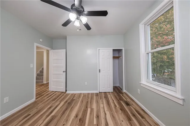 a view of empty room with wooden floor and fan