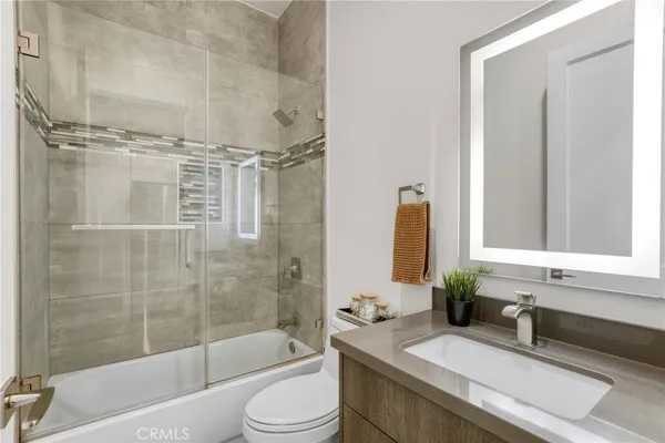 a bathroom with a granite countertop bathtub shower sink vanity and toilet