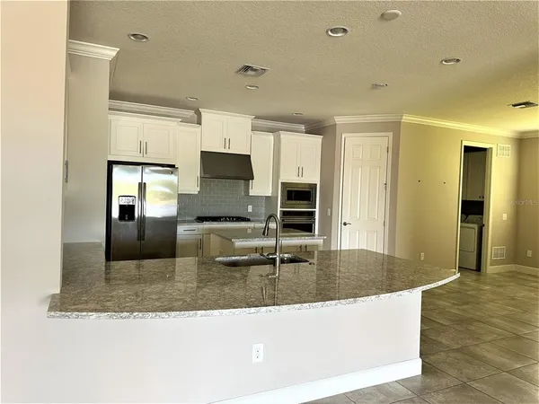 a kitchen with granite countertop a sink a counter top space cabinets and stainless steel appliances