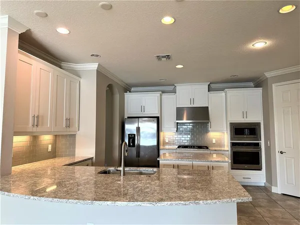 a kitchen with stainless steel appliances granite countertop a sink refrigerator and cabinets