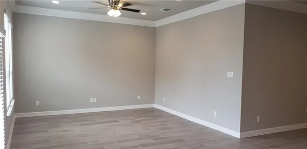 a view of an empty room with a ceiling fan and wooden floor