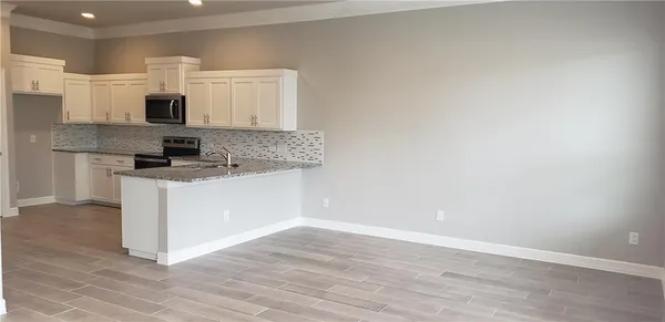 a kitchen with cabinets wooden floor and stainless steel appliances