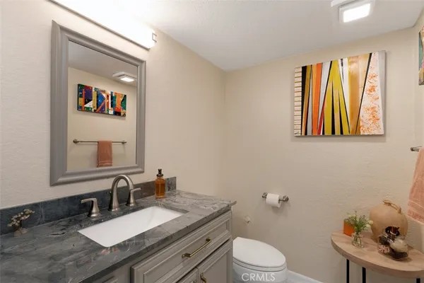 a bathroom with a granite countertop sink mirror vanity and toilet