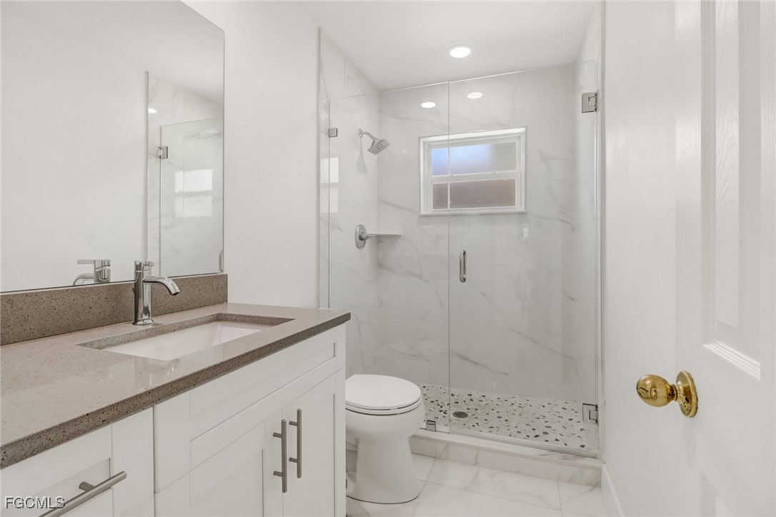 4838 Tudor Drive Cape Coral, FL 33904 - Photo 11 of 20 a bathroom with a granite countertop sink a toilet and shower