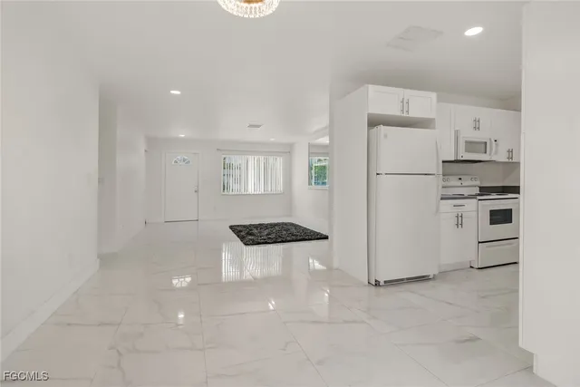 a kitchen with a refrigerator a stove top oven and white cabinets