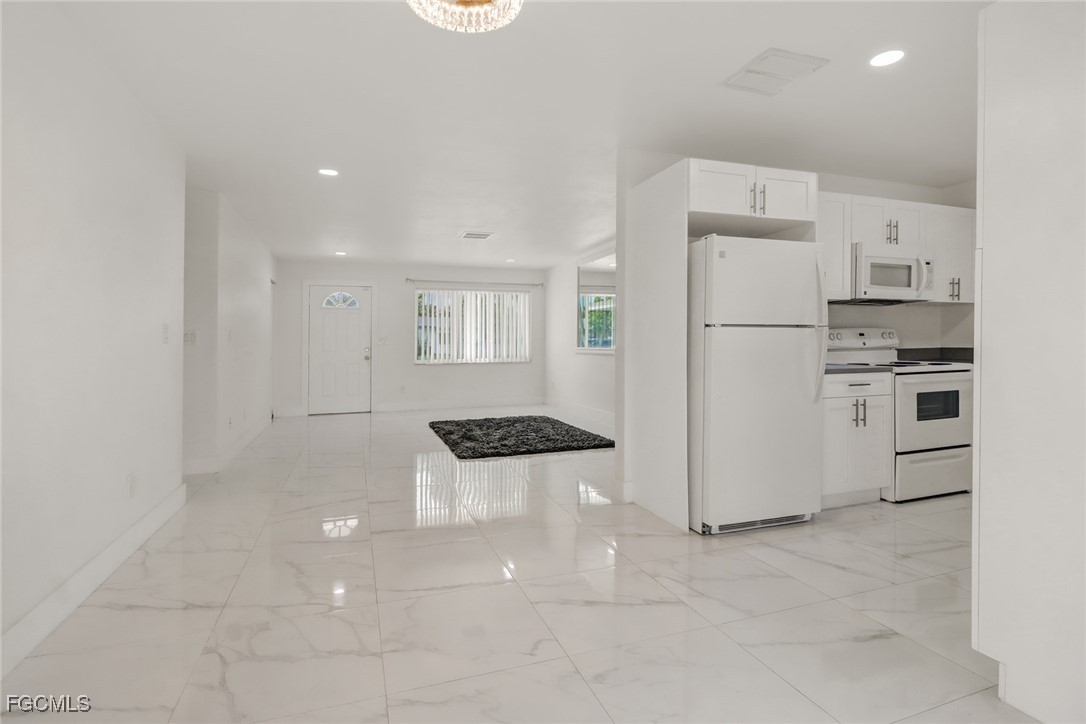 4838 Tudor Drive Cape Coral, FL 33904 - Photo 2 of 20 a kitchen with a refrigerator a stove top oven and white cabinets