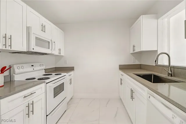 a kitchen with granite countertop white cabinets and white appliances