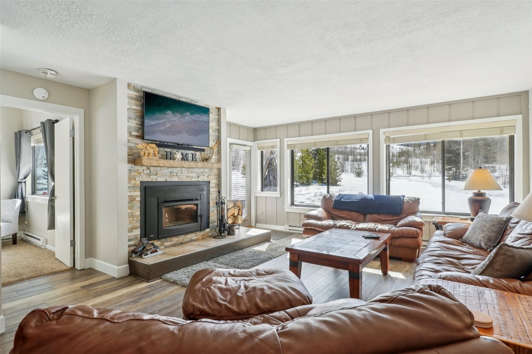 1944 Soda Ridge Road, Unit 1228 Keystone, CO 80435 - Photo 6 of 46 Living room with wood finished floors, baseboards, a fireplace, a textured ceiling, and baseboard heating