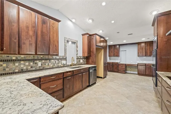 a large kitchen with stainless steel appliances a large counter top a stove a sink and a microwave
