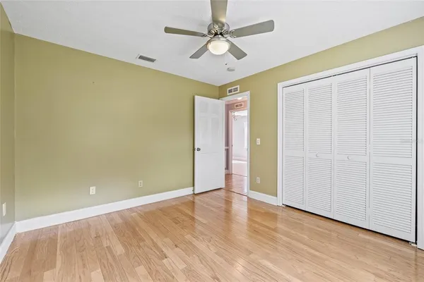 a view of empty room with wooden floor and fan