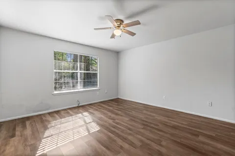 a view of an empty room with wooden floor and a window