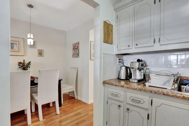 a kitchen with granite countertop white cabinets and wooden floor
