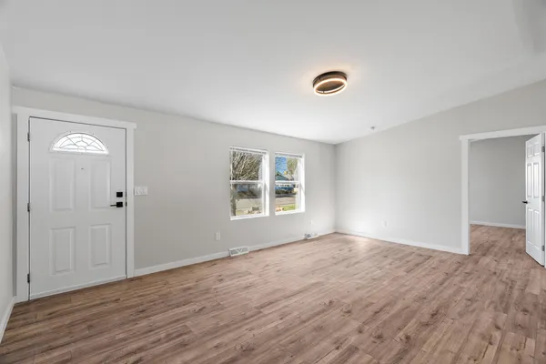 a view of an empty room with wooden floor and a window