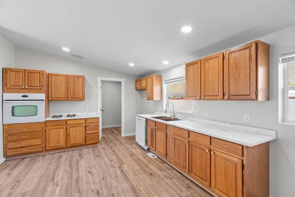a kitchen with stainless steel appliances granite countertop a sink cabinets and wooden floor
