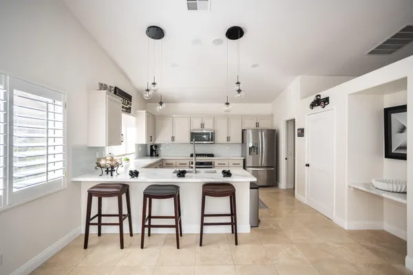 a kitchen with stainless steel appliances granite countertop a sink a stove a refrigerator cabinets a dining table and chairs