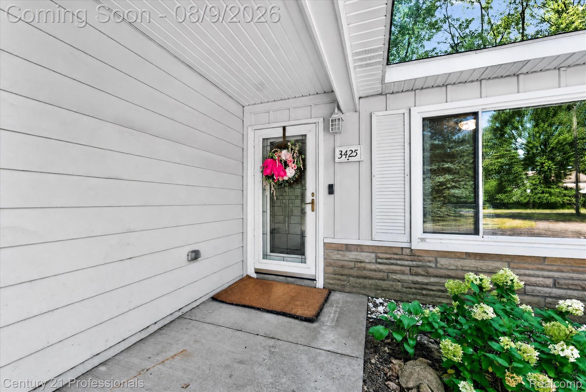 3425 McClure Road Troy, MI 48084 - Photo 3 of 34 White horizontal siding with a glass-paneled entry door and window with louvered shutters