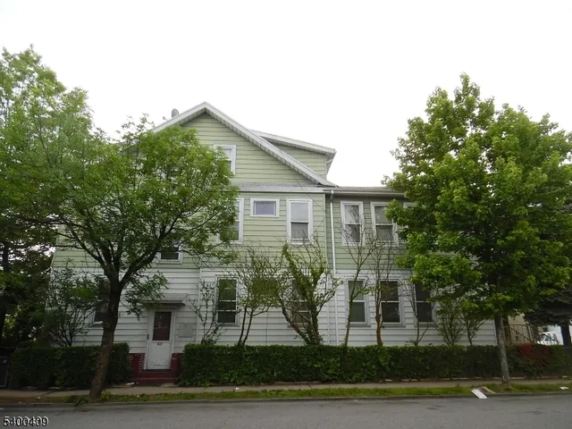 a view of a yard in front of a brick house with large windows