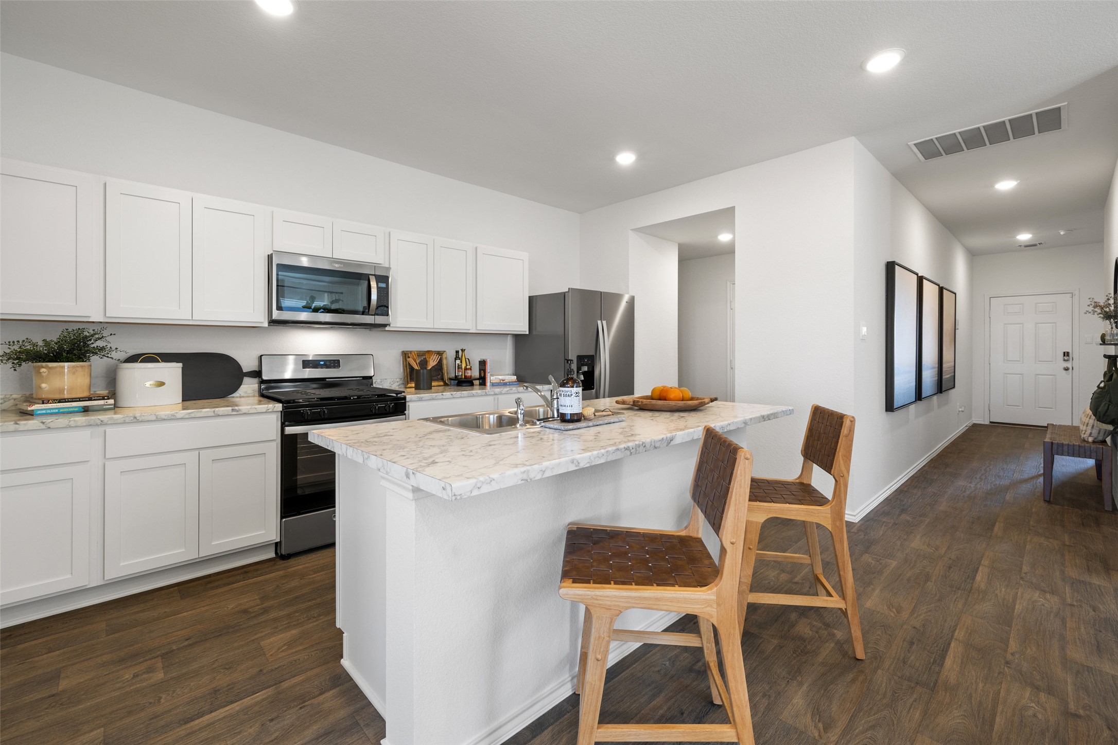 879 Arnold Loop Kyle, TX 78640 - Photo 17 of 33 a kitchen with a dining table chairs refrigerator and microwave