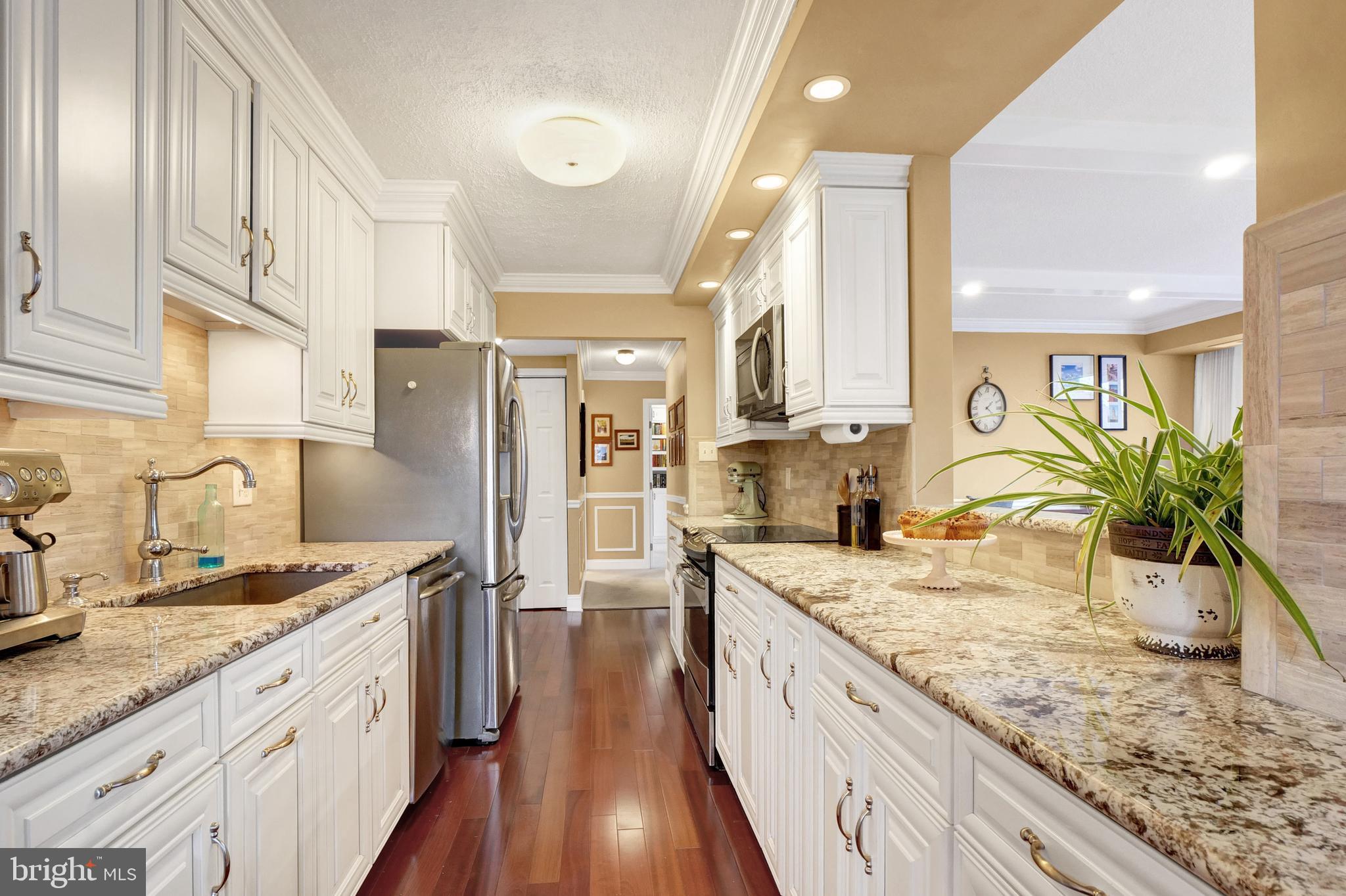 a large kitchen with stainless steel appliances granite countertop a lot of counter space and wooden floor