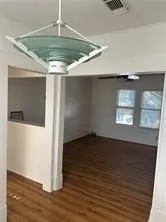 a view of an empty room with wooden floor and a ceiling fan