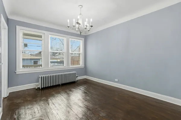 a view of an empty room with wooden floor and windows