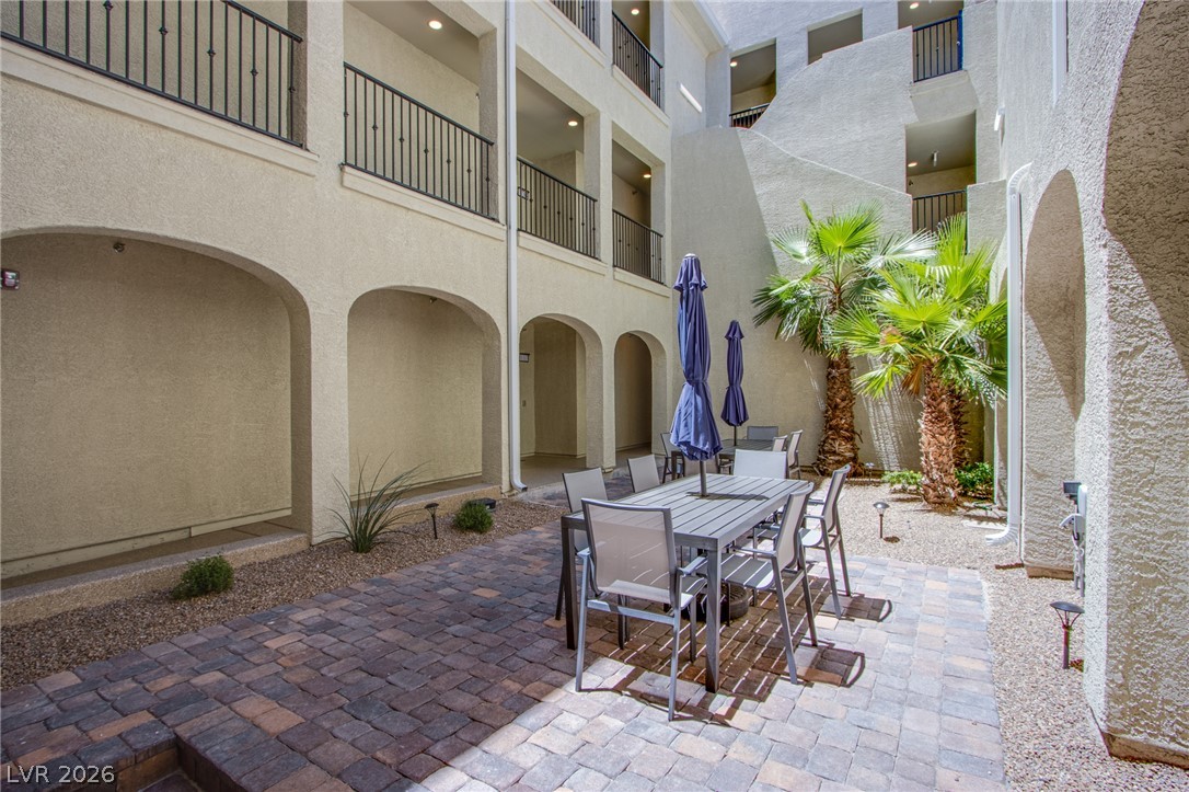 An inviting courtyard features paved brick flooring surrounded by arched stucco architecture.
