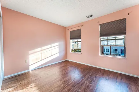 an empty room with wooden floor and windows