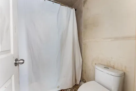 a white toilet sitting next to a shower