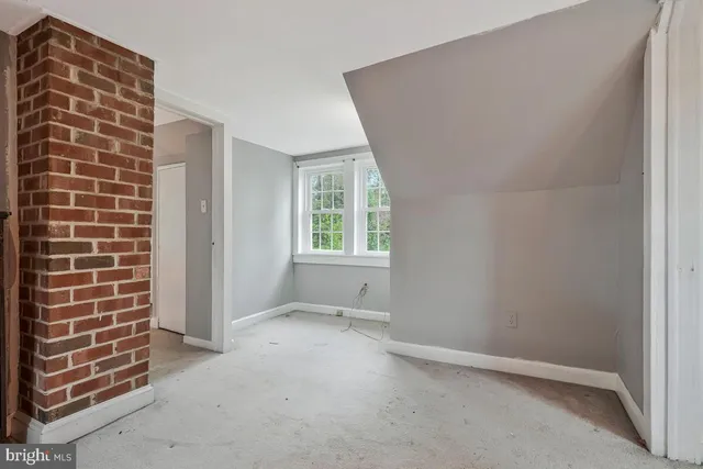 en empty room with a fireplace and a chandelier fan