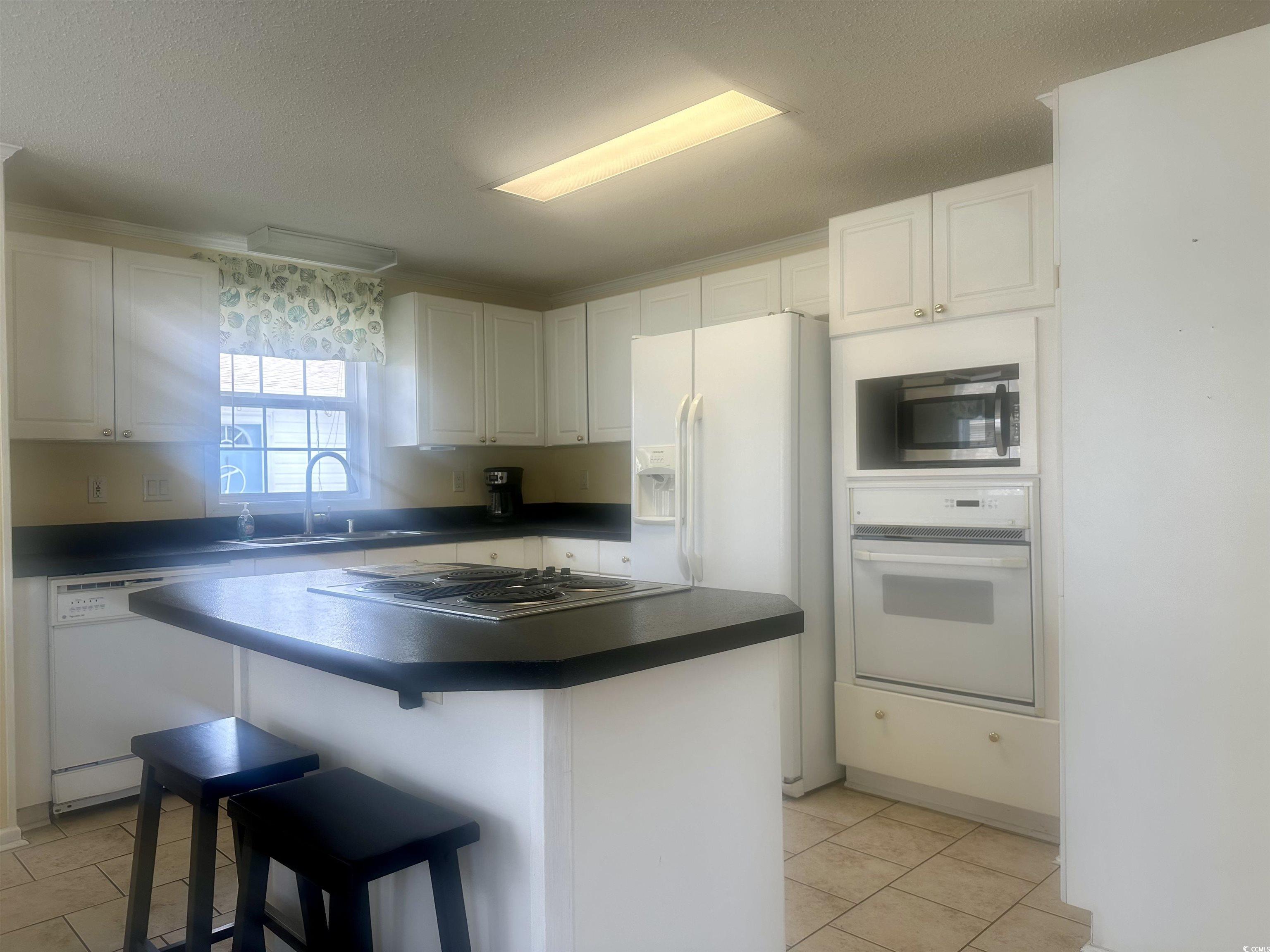 1752 Mason Circle Murrells Inlet, SC 29576 - Photo 25 of 31 Kitchen with a breakfast bar, white cabinets, light tile patterned floors, and white appliances