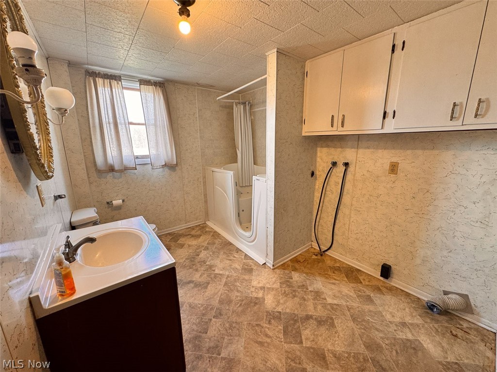 15 Glecoe Road Southwest Carrollton, OH 44615 - Photo 45 of 50 Bathroom featuring vanity, shower / bath combination with curtain, stone finish floors, washer / clothes dryer, and wallpapered walls