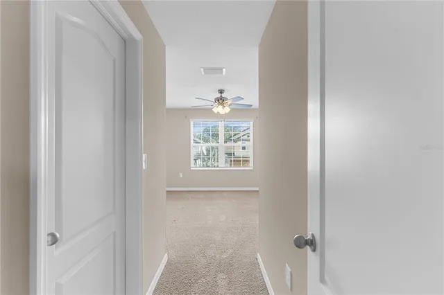 an empty room with windows and ceiling fan