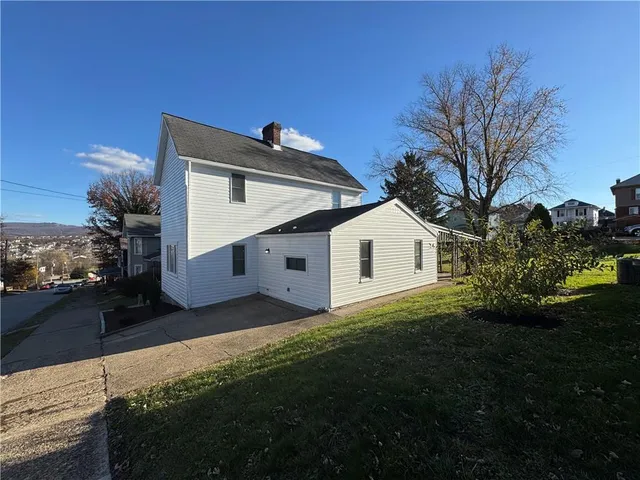 a front view of house with yard and trees in the background