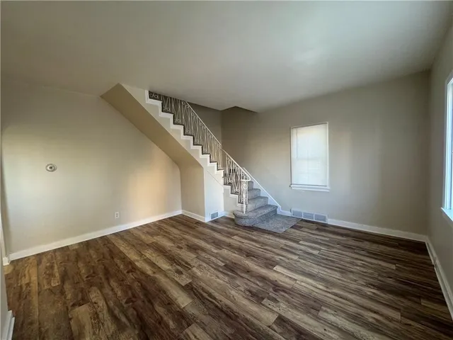 a view of an empty room with stairs and a window