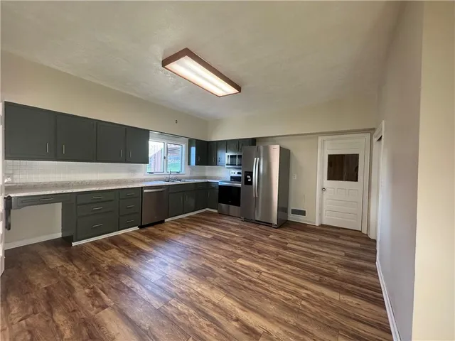 a large kitchen with kitchen island a sink stainless steel appliances and cabinets