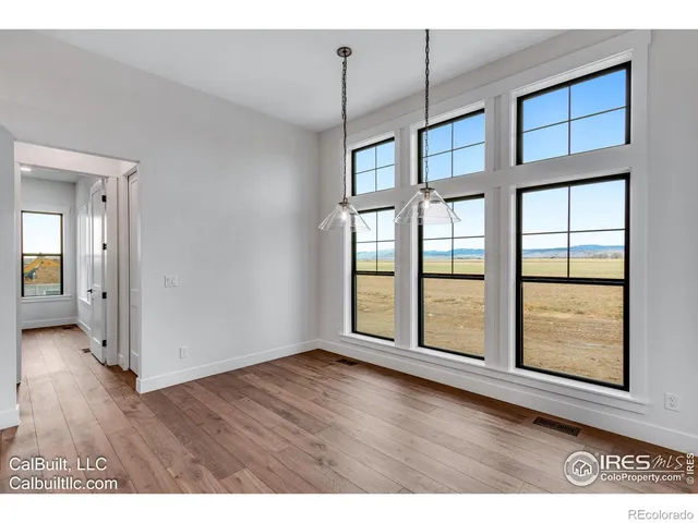 a view of an empty room with window and wooden floor