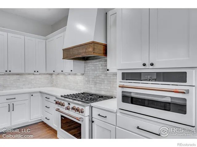 a kitchen with granite countertop white cabinets and appliances