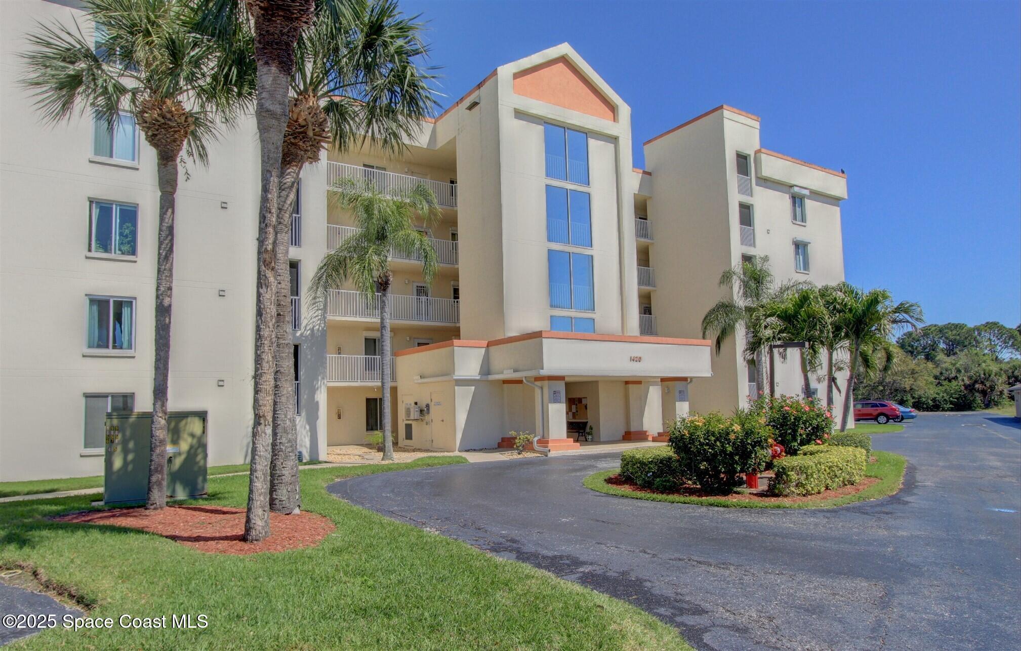 a front view of a multi story residential apartment building with yard and green space