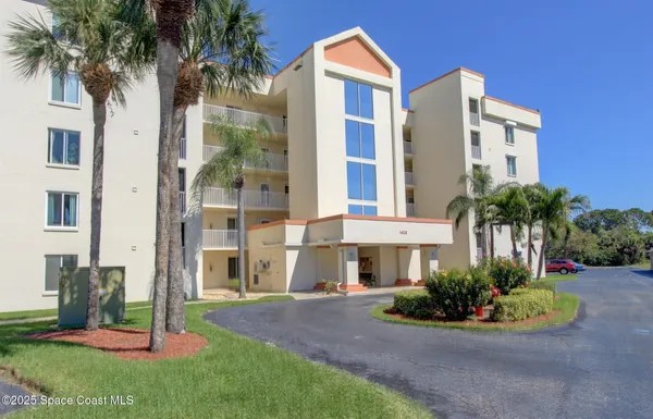 a front view of a multi story residential apartment building with yard and green space