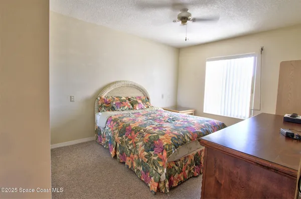 a bedroom with a bed a dresser and potted plant
