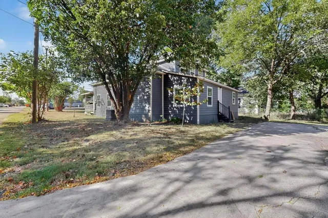 a front view of a house with a garden and trees