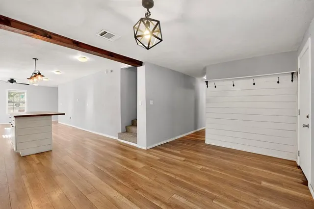 a view of empty room with wooden floor and fan
