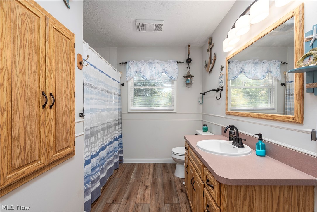 75 Houghton Road Northfield, OH 44067 - Photo 21 of 48 Bathroom with wood-finish flooring, a wood vanity with a pink countertop, and a white sink with a black faucet