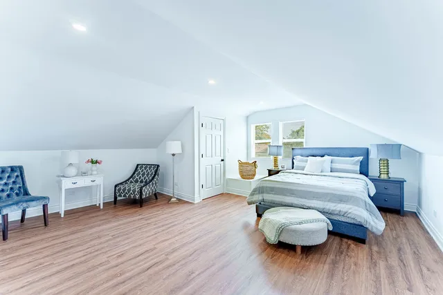 a spacious bedroom with a bed and wooden floor